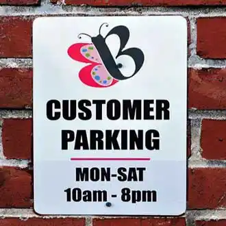 Customer parking sign with butterfly company logo and hours reading Monday through Saturday 10am to 8pm