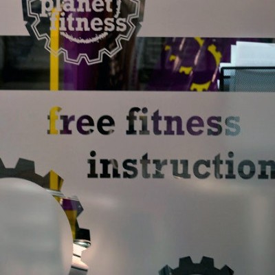 Planet Fitness indoor glass sign which reads free fitness instructions.